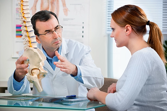 Doctor In Lab Coat Gesturing To Spine Demonstratively
